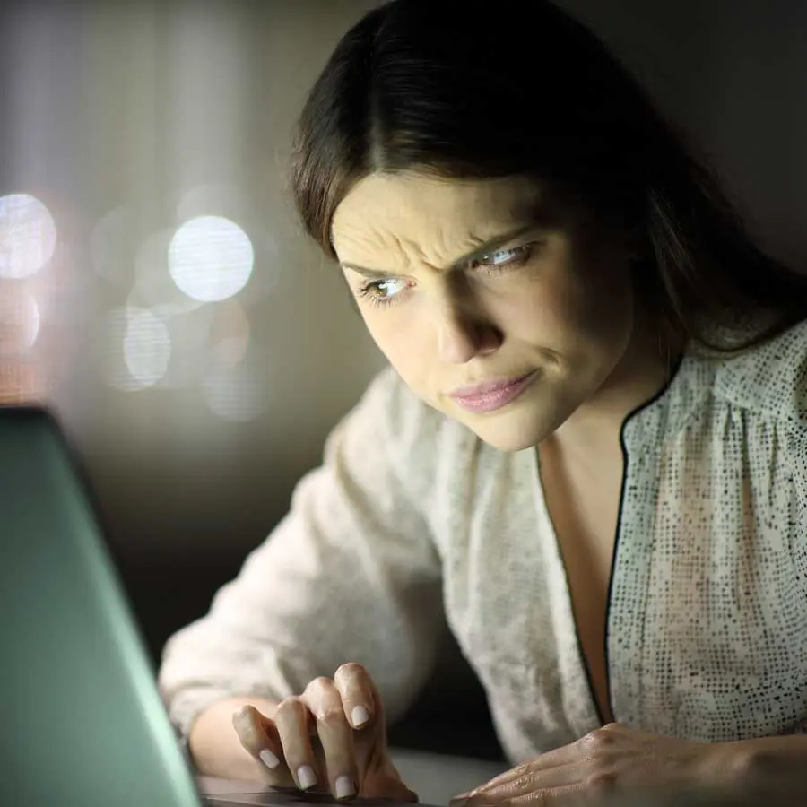 Young woman eyeing her laptop suspiciously