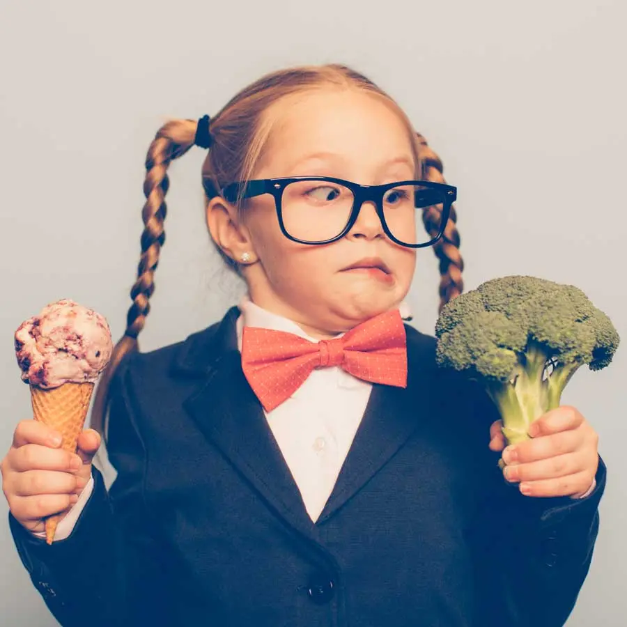 A girl has the choice between ice cream and vegetable