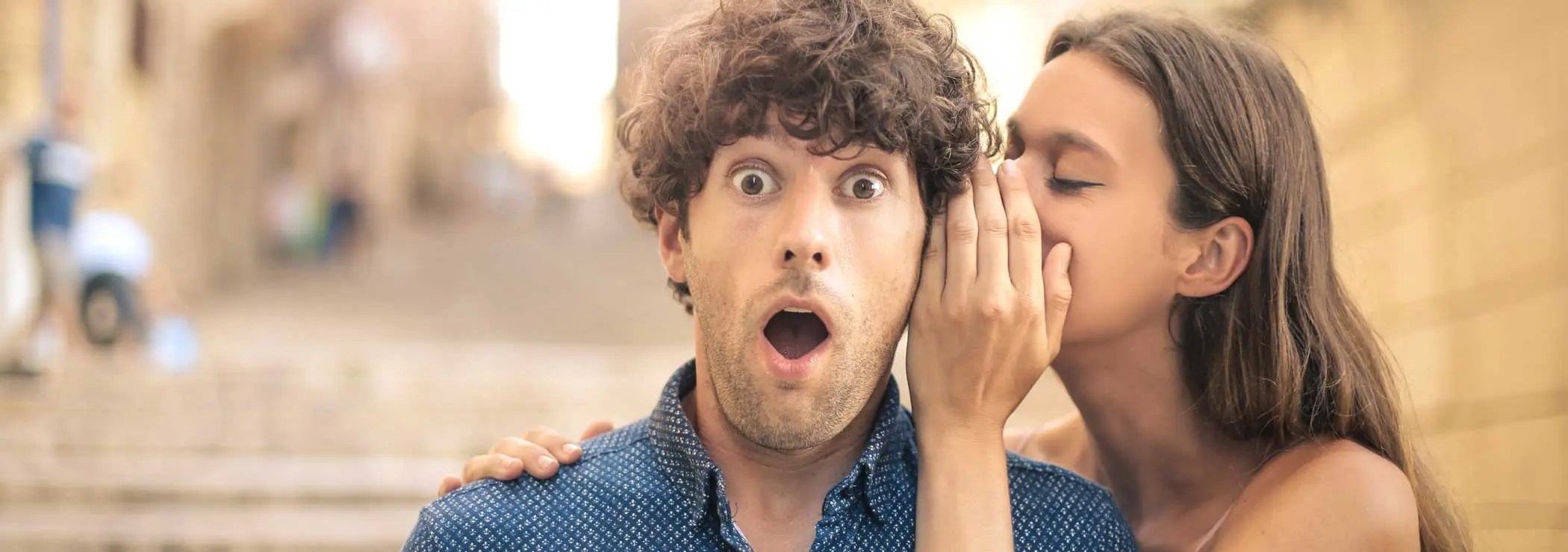 Frau flüstert Mann ins Ohr