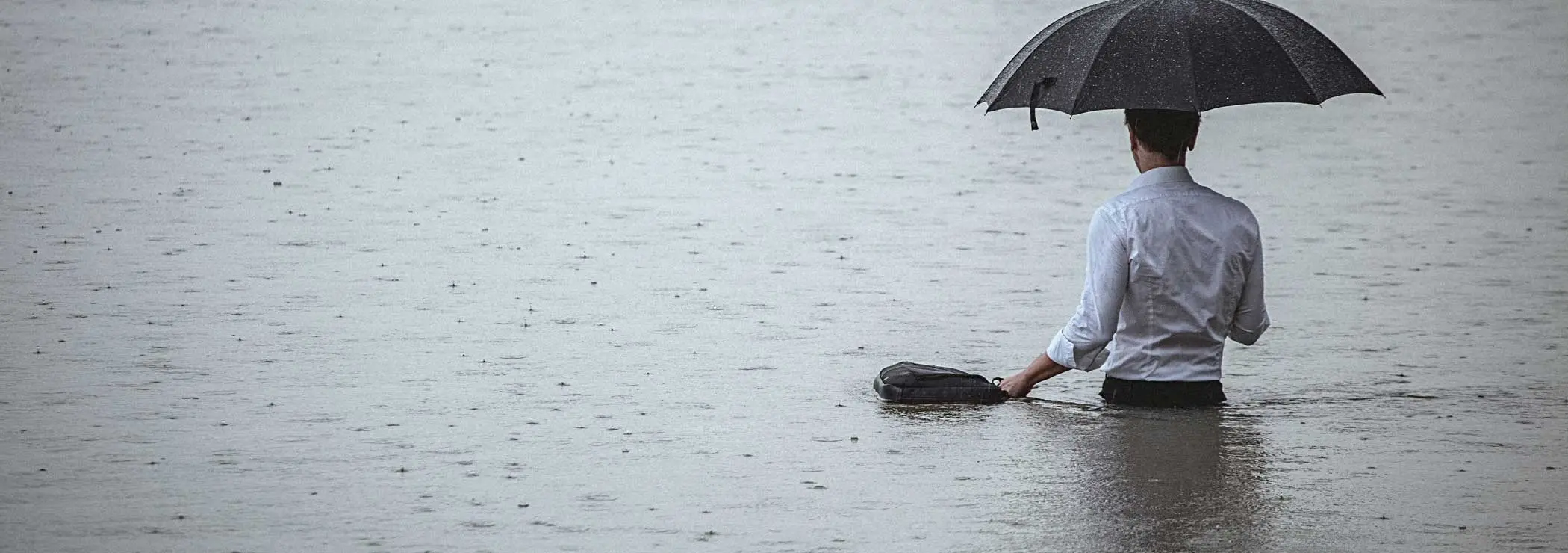 Ein Mann im Hemd steht hüfttief im Wasser 