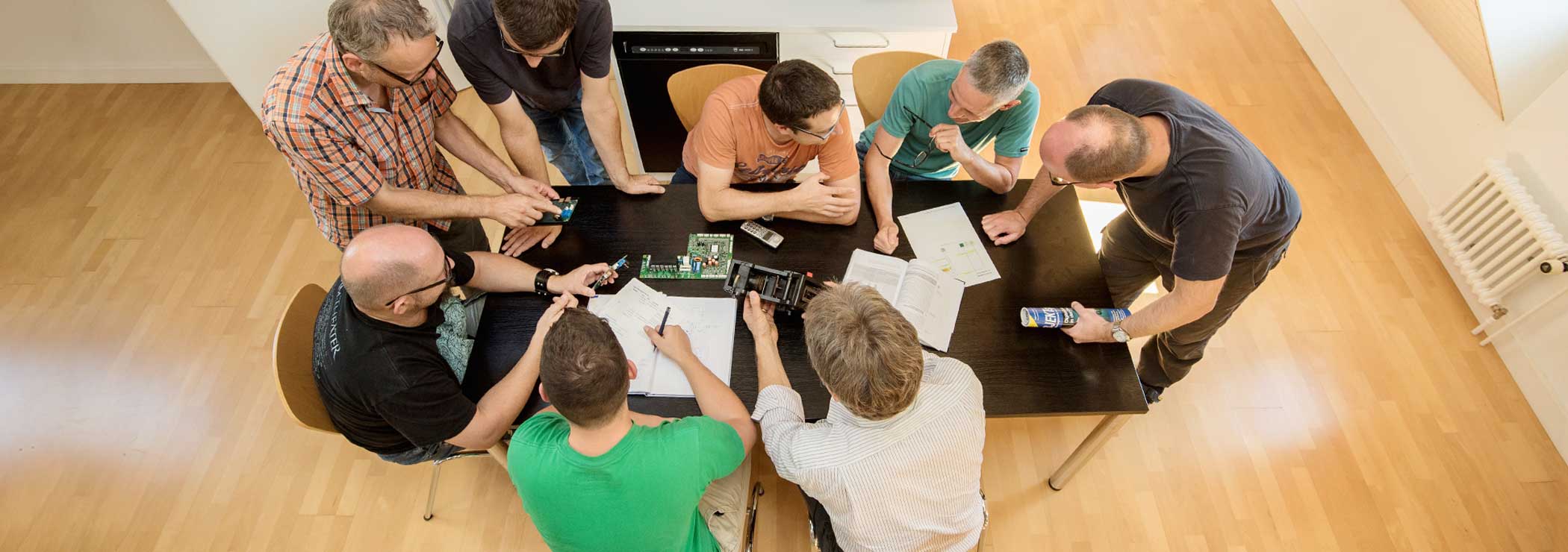 From above: engineers around table, discussing