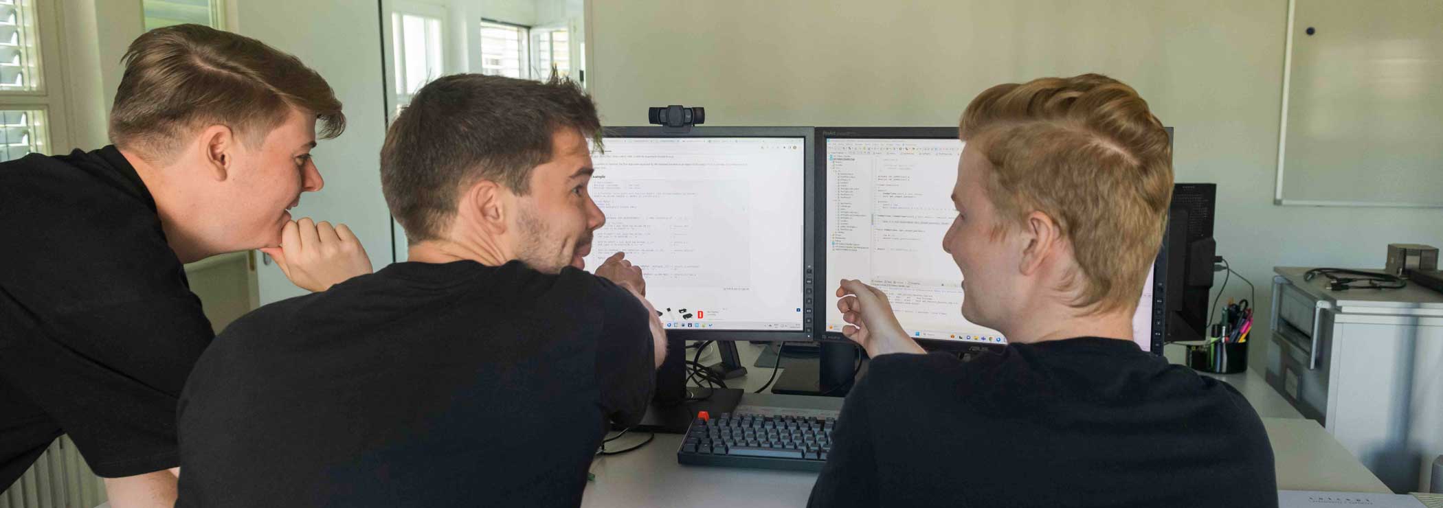 Three seated young men discussing in front of the screen