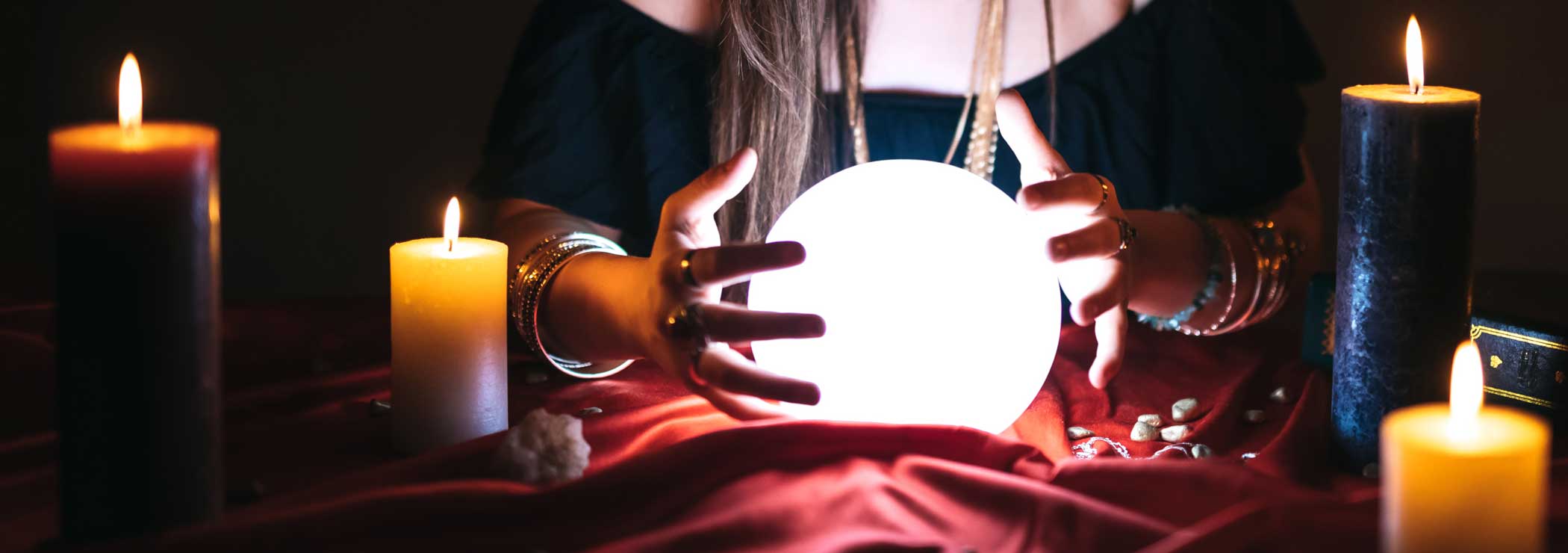 A fortune teller holds hands around a crystal ball