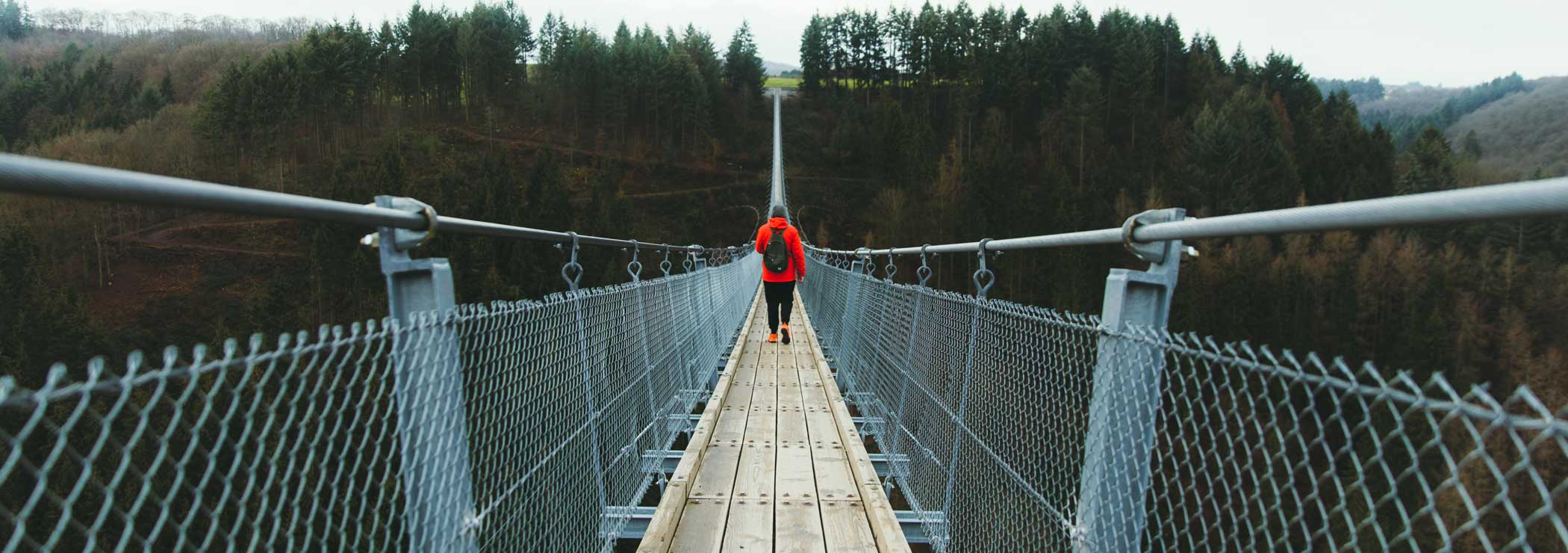 Man walking on suspension bridge