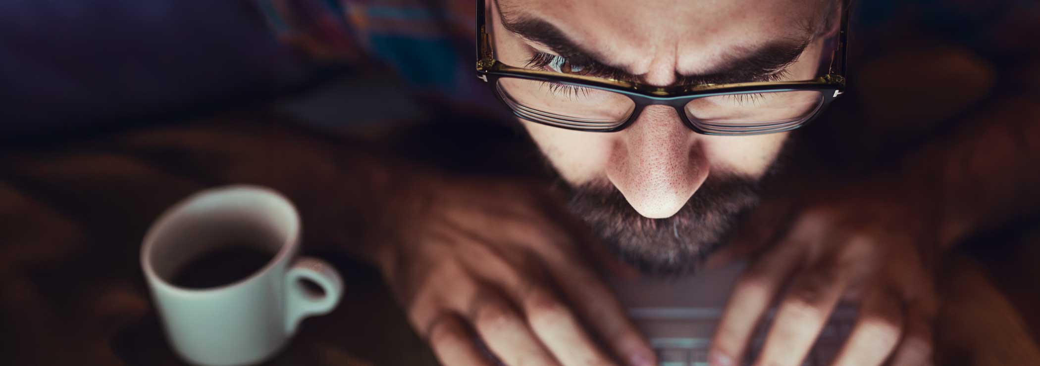 A man with glasses looks at a screen with raised eyebrows.