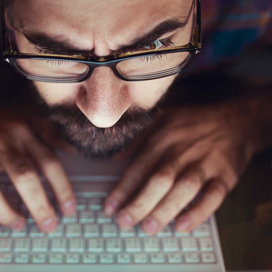 A man with glasses looks at a screen with raised eyebrows.