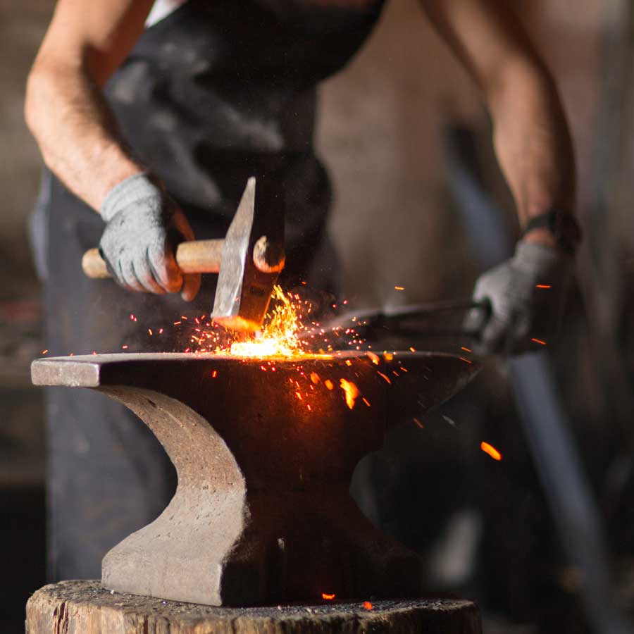Schmied schmiedet ein heisses Werkstück auf dem Amboss 