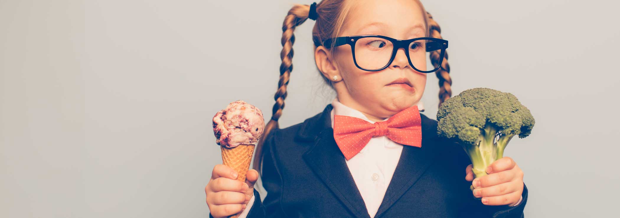 A girl has the choice between ice cream and broccoli