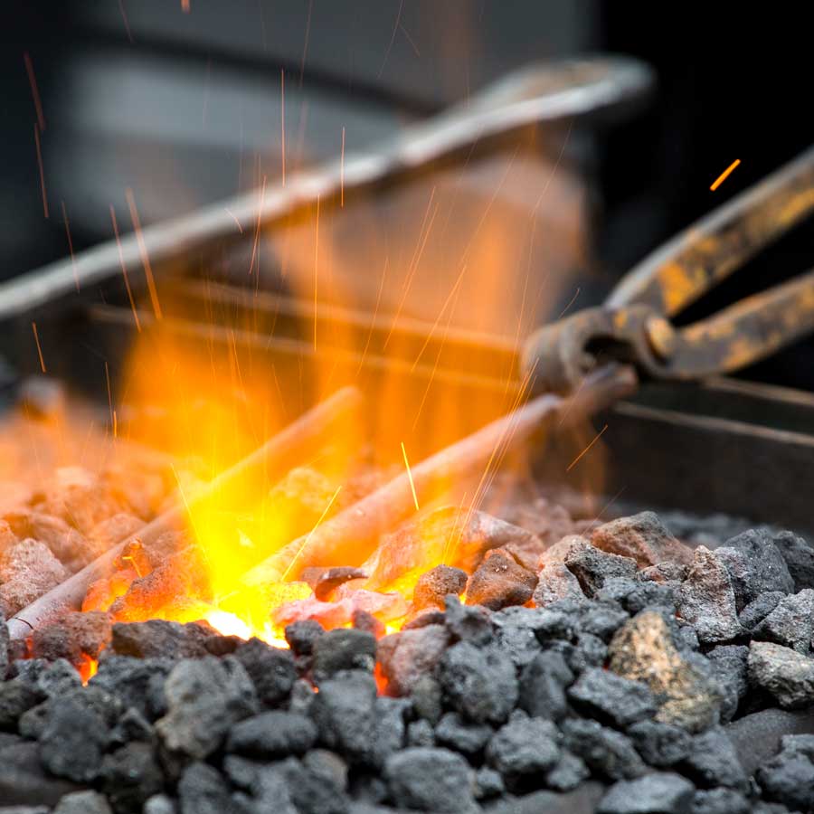 Ein Stück Metall wird in der Schmiedeesse erhitzt