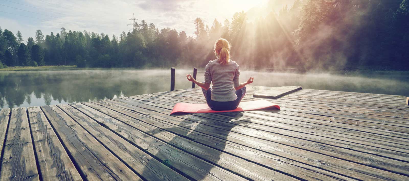Woman meditates at a lake