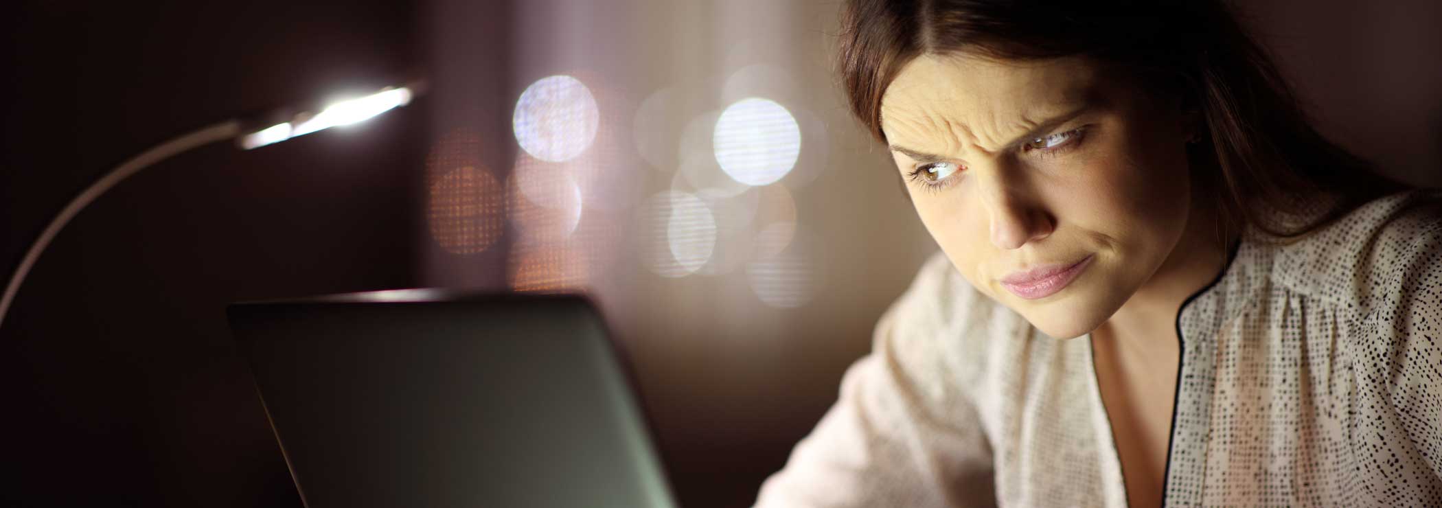 Young woman eyeing her laptop suspiciously