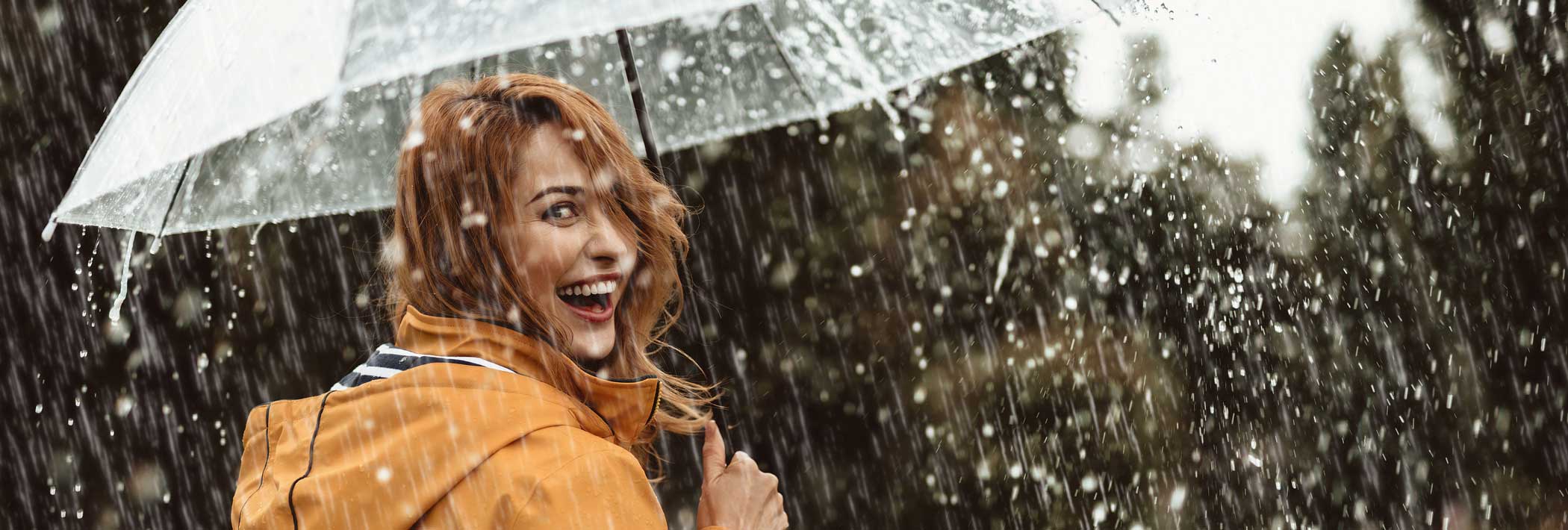 A joyful woman with an umbrella looks over her shoulder
