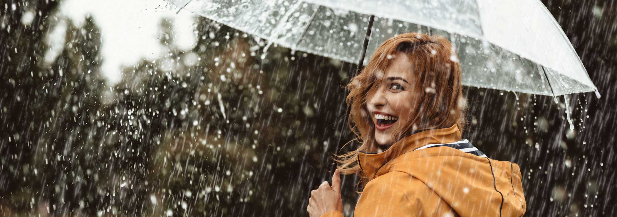 A joyful woman with an umbrella looks over her shoulder